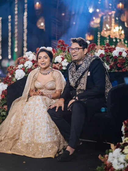 A candid shot of the couple laughing together on stage during their sangeet, enjoying a performance.