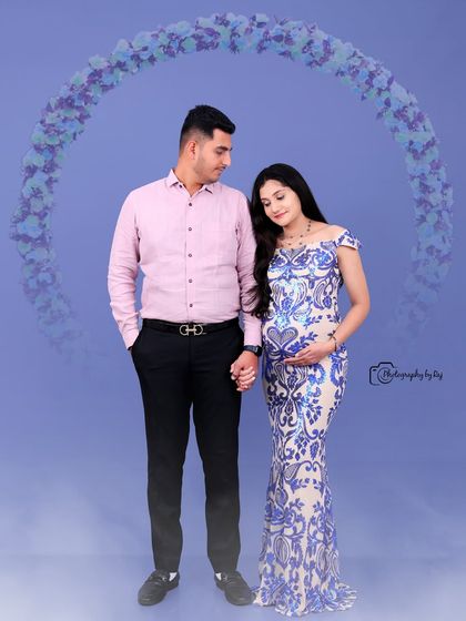A romantic studio portrait of a couple, with the mother-to-be in a blue and white sequined gown.