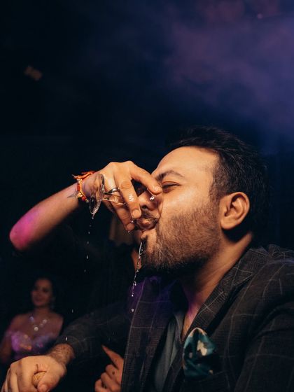 A fun, candid moment of a guest taking a shot. This image adds to the story of a lively and uninhibited wedding party.