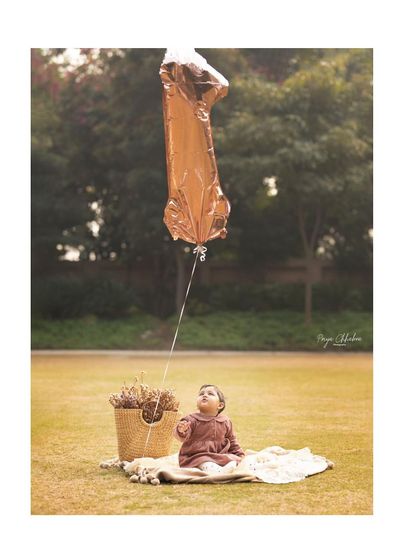 A single balloon and a world of wonder. This shot from an outdoor first birthday session captures the simple magic of being one year old, looking up at the world with awe.