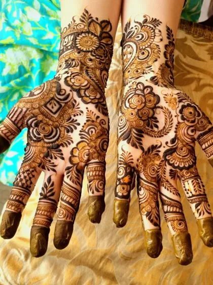 Freshly applied Indo-Arabic henna with its dark paste. You can see the mix of styles, from the floral motifs to the detailed lines and dots that fill the entire hand.