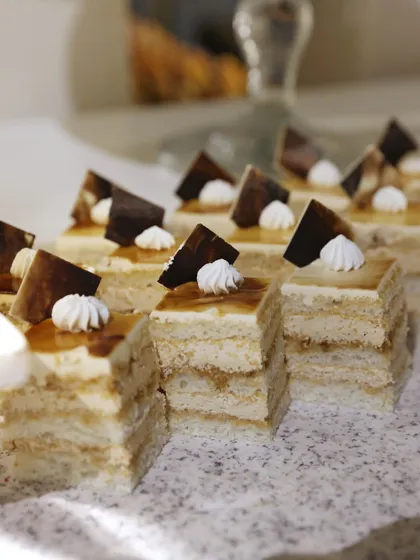 Layers of light sponge and cream create these perfect little opera cakes, each topped with a dollop of meringue and a chocolate triangle.