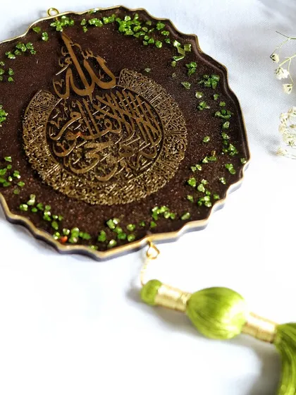 An elegant flat lay of a resin art piece with Islamic calligraphy, styled with delicate baby's breath flowers to create a soft and spiritual mood.