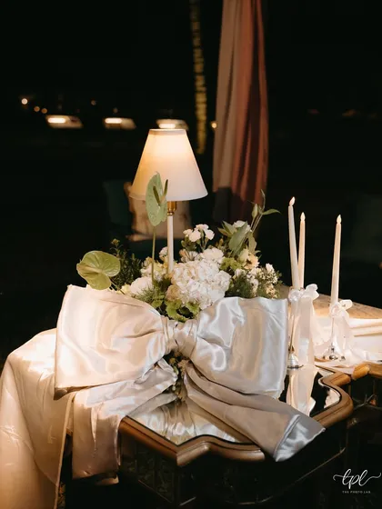 An elegant table centerpiece with a lamp and a large silver bow, creating a timeless and romantic look.