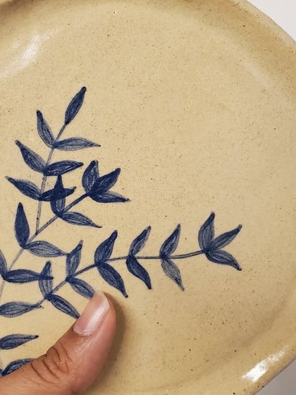 A close-up on the brushstrokes of the hand-painted foliage. The slight imperfections are a mark of the handmade process and give each plate its unique character.