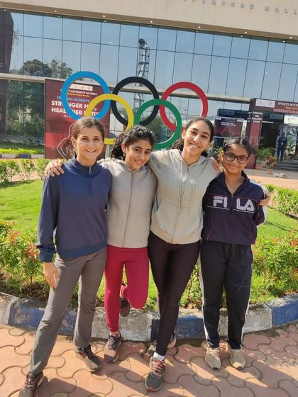 Our female athletes standing together in front of the Olympic rings, celebrating the power of women in sports.