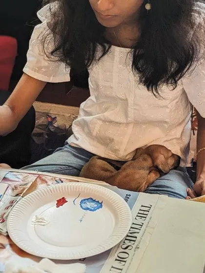 A sleepy puppy finds the perfect napping spot on a participant's lap during a relaxing art session.