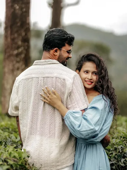 A close-up, happy portrait of a couple in a tea garden, their genuine smiles making the photo feel warm and personal.