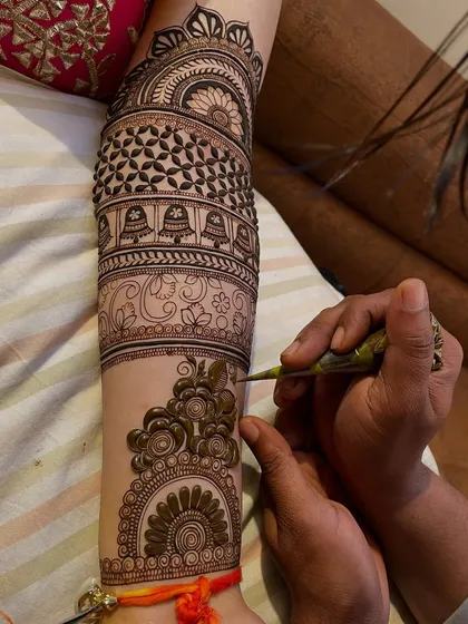 This arm design features multiple bands, including hanging bells (jhumkis) and floral patterns, creating a layered and rich look.