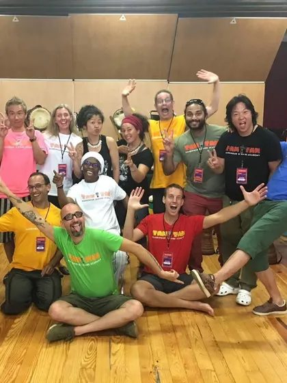A fun, energetic group photo from one of the Tam Tam Mandingue Djembe Academy workshops. The joy and camaraderie are evident. This is the spirit of 'Wassa Wassa', the feeling of happiness we chase.