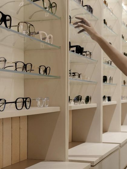 A close-up of the eyewear display shows the delicate balance of glass shelving and minimal supports, ensuring the focus remains entirely on the products.