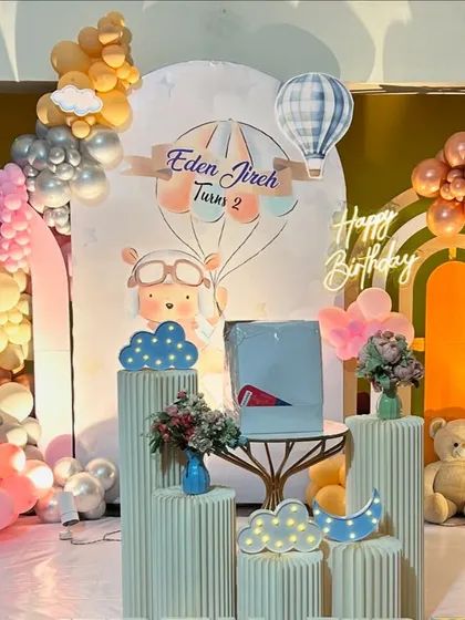 A charming hot air balloon and teddy bear theme in pastel and retro colors. This setup includes multiple arches, balloon clouds, and light-up elements for a dreamy second birthday.