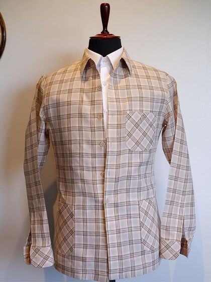 Effortlessly embodying a blend of classic sophistication and modern style, this beige plaid overshirt elevates your wardrobe with its timeless charm.
