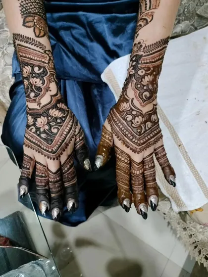 A stunning view of matching bridal henna for both hands. The symmetrical design features lotus-inspired patterns and chevron bands on the wrist, creating a powerful and cohesive bridal statement.