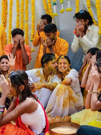 A close-up shot of the fun and messy Haldi celebration, capturing the genuine reactions of the couple and their friends.