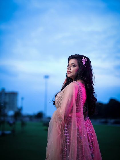 A profile shot of a woman against a blue evening sky, with soft pink light highlighting her.