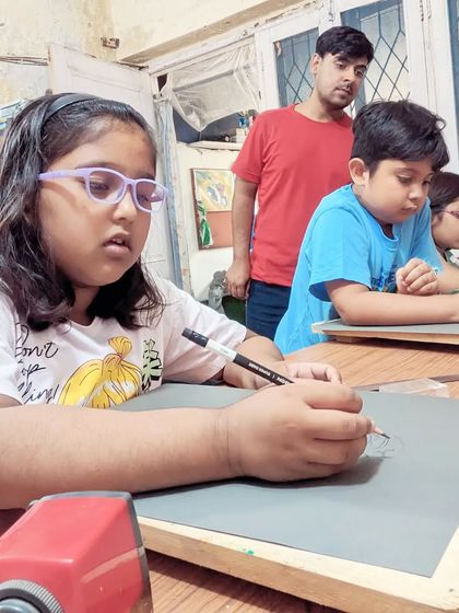 A student deeply focused on her drawing, with the instructor looking on to provide support when needed.
