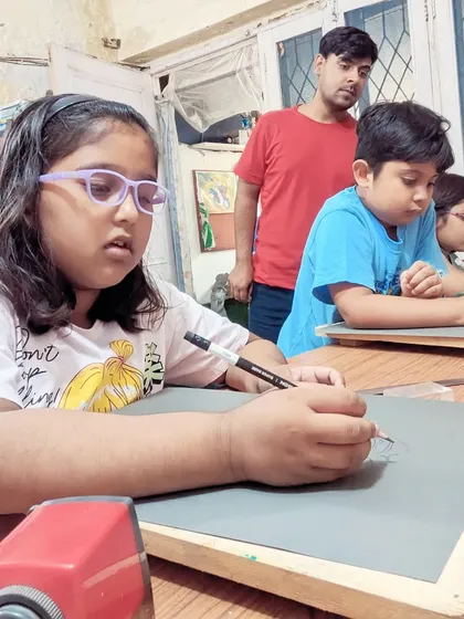 A student deeply focused on her drawing, with the instructor looking on to provide support when needed.