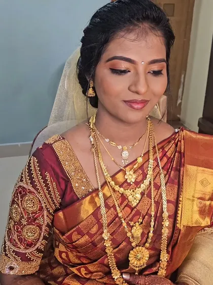 A Christian wedding look with a traditional maroon saree and gold jewelry, paired with a white veil.