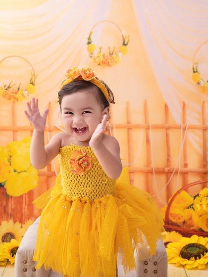 A little ray of sunshine. This baby girl's joyful laugh is the centerpiece of this bright and cheerful sunflower-themed shoot.