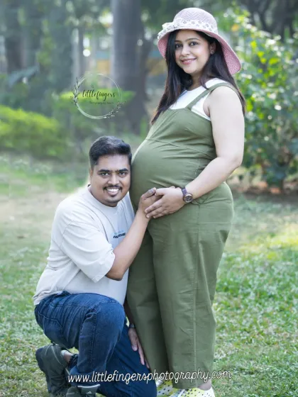 A happy father-to-be listens to his wife's belly during their casual outdoor maternity shoot. Their relaxed outfits and genuine smiles capture a moment of pure joy.