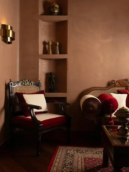 A private consultation nook, where traditional Indian furniture and rich red textiles create a sense of heritage and luxury.