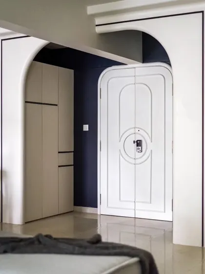 The arched passage, with its deep blue accent wall and custom door, creates a sense of drama and anticipation as you move through the home.