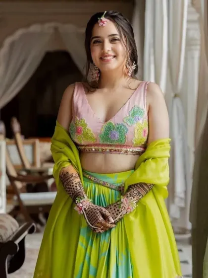 A happy client ready for her mehndi function. The design on her hands perfectly complements her beautiful green and pink lehenga.