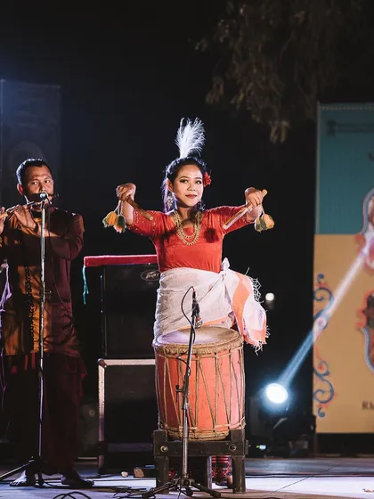 A performer from Rhythms of Manipur smiles at the audience while playing her instrument. Capturing these moments of connection between the artist and the crowd is a key part of my style.