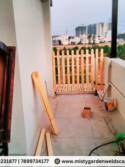 A small picket fence gate under construction, designed to provide access while maintaining the boundary of a balcony or terrace area.
