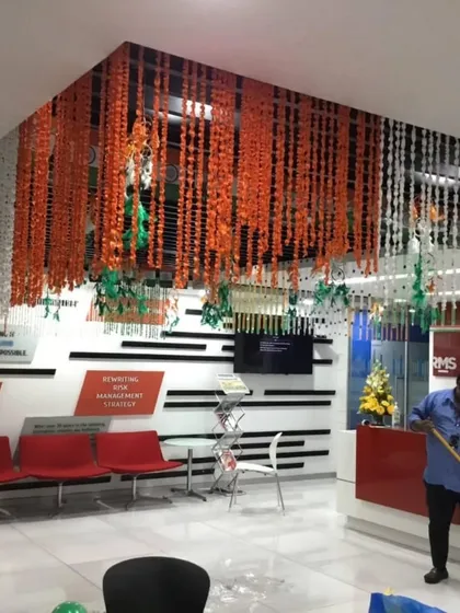 An office reception area transformed with a ceiling installation of marigold and white flower strings, arranged to represent the Indian flag.