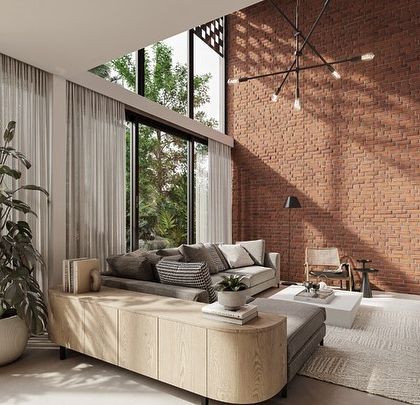 In our Kolgaon project, the double-height living space is defined by a feature brick wall that continues from the exterior. This emphasizes the connection between architecture and interiors, creating a cohesive material narrative.