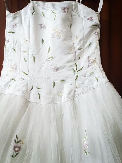 This unique white gown features a satin bodice with delicate green and purple floral embroidery. It's a perfect rental for a spring or garden-themed photoshoot.