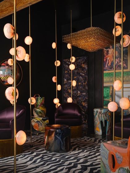 A wider view of the Bocci 84 series installation, showing how the vertical lights create a dramatic, room-dividing effect in a luxurious lounge setting.