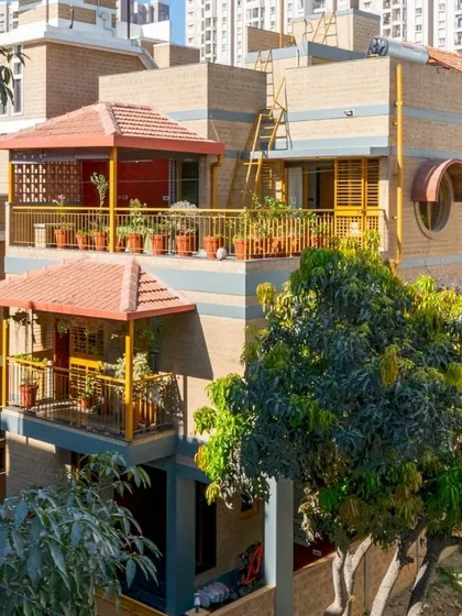 Another perspective of the house, highlighting the texture of the earth blocks and the greenery on the balconies.
