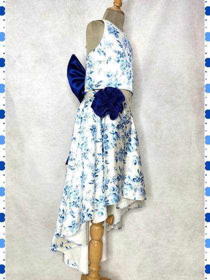 Another view of our blue floral high-low skirt set, showing the dramatic bow and flower detail that makes it a true showstopper for any daytime event.