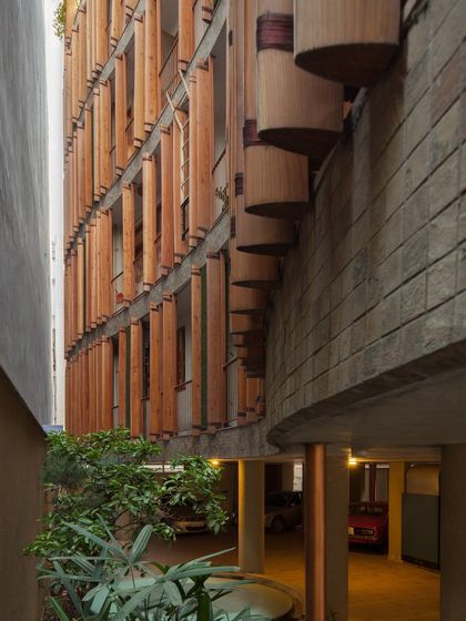 A detail shot showing the interplay between the curved concrete structure and the vertical wooden louvres of the Outré House, a testament to our exploration of material and form.