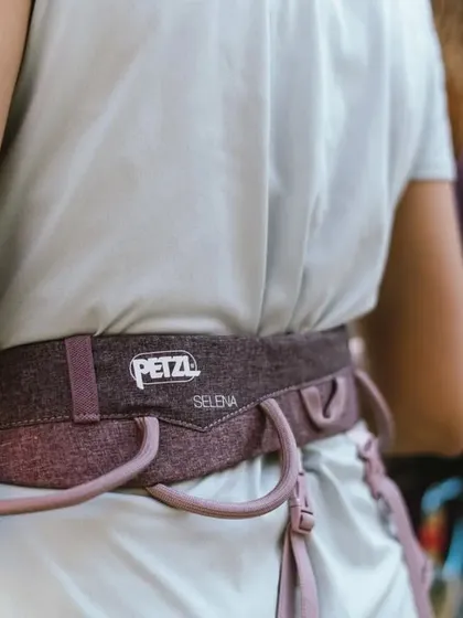 A climber wearing a Petzl Selena harness. We are proud to partner with brands that help us create access to quality equipment.