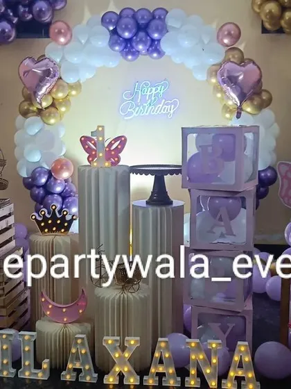 A beautiful butterfly theme with purple, white, and gold balloons. The setup includes "BABY" boxes and a light-up name sign for a glamorous touch.