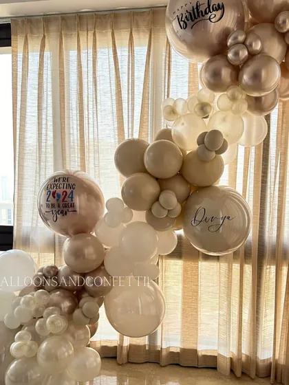 Another view of the neutral balloon installation, featuring a custom printed balloon for a baby announcement: 'We're expecting 2024 to be a great year'.