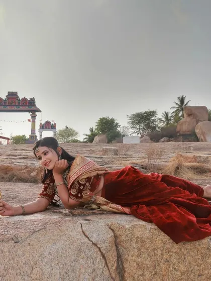 This wide shot incorporates the surrounding environment, with a traditional temple arch visible in the distance. It adds context and a sense of place to the portrait.