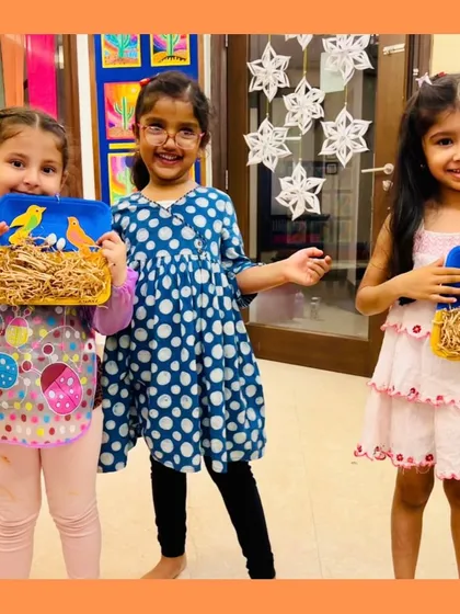 Three happy students showing off their bird's nest craft. Art plus laughter equals childhood magic, and these smiles prove it.