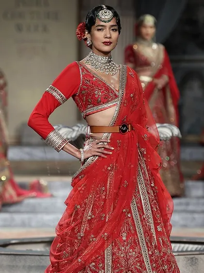 A classic red lehenga with a modern twist. The belted waist and full-sleeve blouse offer a contemporary take on traditional bridal wear, perfect for the fashion-forward bride.