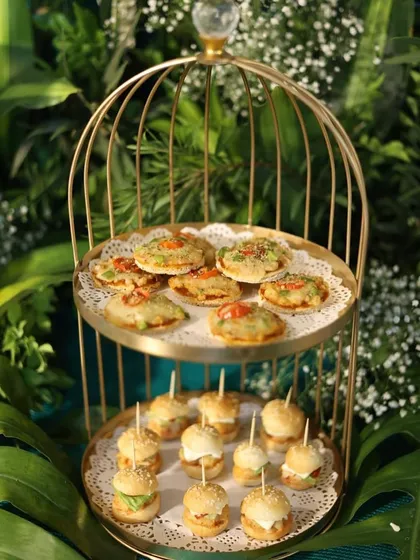 Our "mini food for the mini you" concept is a favorite. Here are our freshly made mini pizzas and burgers, served in a beautiful golden birdcage stand, perfect for a whimsical and delicious touch.