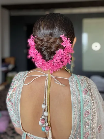 The back view of the wedding bun, showing how the pink floral garland is wrapped around the base for a full and festive look.