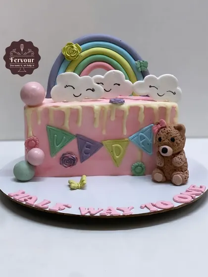 A "Half way to one" cake to celebrate a 6-month milestone. This cake features a cute teddy bear, a rainbow, and colourful bunting.
