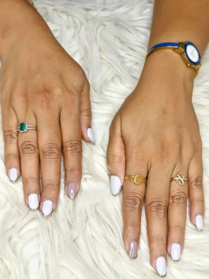A clean and modern look with bright white polish and a sheer, glittery accent on the ring finger for a subtle contrast.