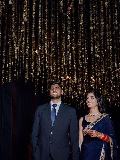 A couple making their entrance under a ceiling of cascading golden tassels. This lighting installation creates a warm, sparkling canopy that makes for a stunning photograph and a memorable moment.