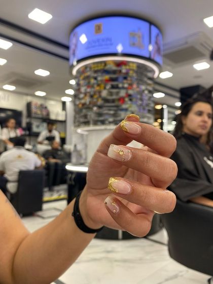 A beautiful set of nails with gold leaf and abstract white details, created by one of my talented students.