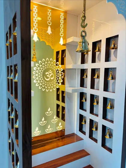 A close-up of the mandir's interior, showing the backlit 'Om' symbol and the small brass bells hanging in the side niches, creating a divine atmosphere.